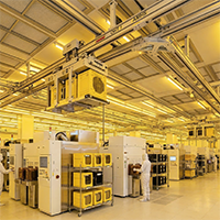Inside a high-tech automated semiconductor manufacturing facility with yellow lighting.